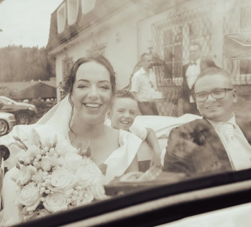 Svadobná fotografia ženích s nevestou sedia v aute pred penziónom Lucs Heľpa.